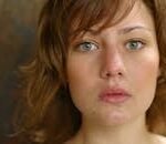 A close-up portrait capturing a young woman's natural beauty with a serious expression.