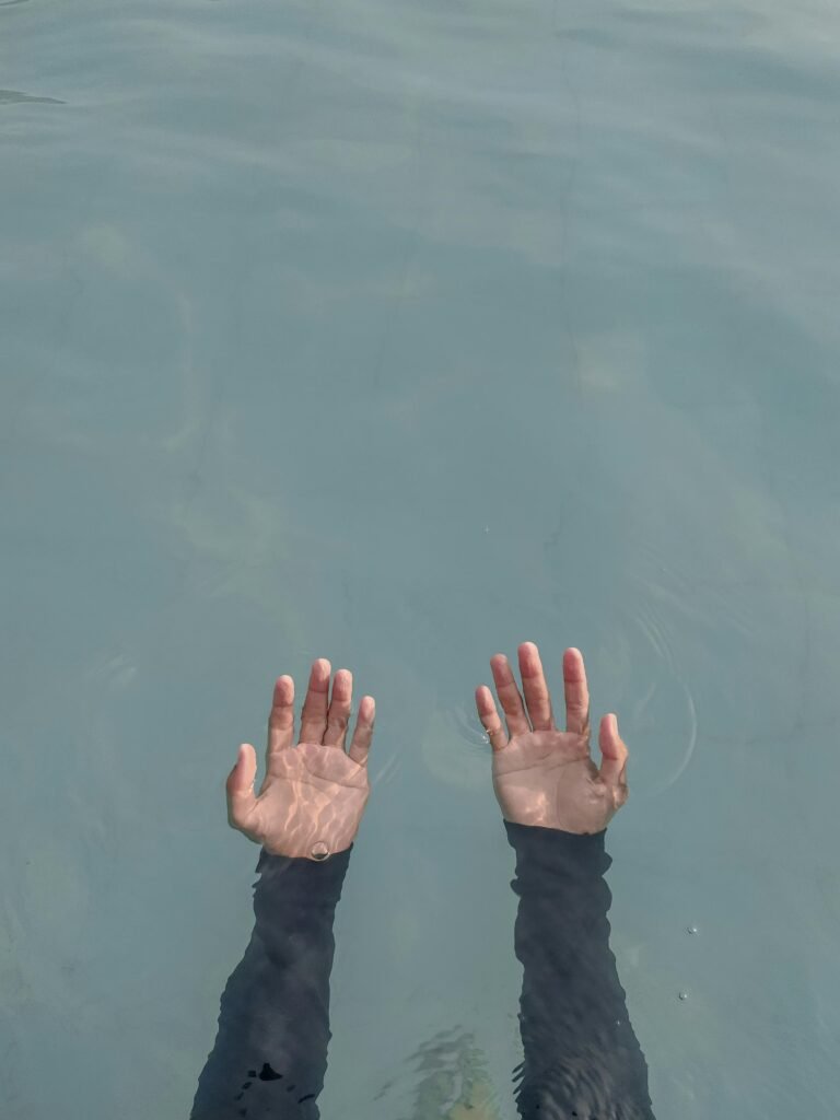 Serene image of hands submerged in water, capturing tranquility and reflection.