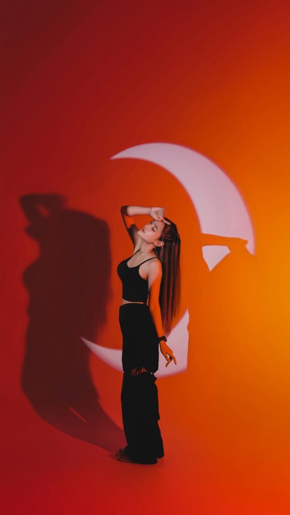 A captivating portrait of a woman in front of a crescent moon shadow on an orange backdrop.