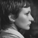Monochromatic side-profile portrait of a woman with short hair taken indoors in a studio setting.